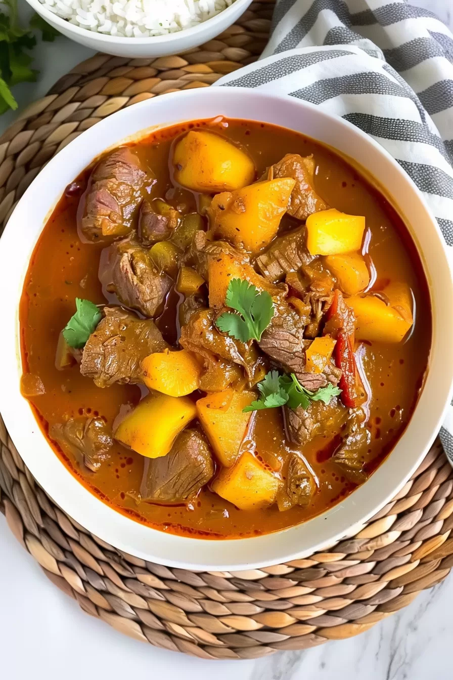 A bowl of homemade slow cooker beef curry massaman with vibrant colors, including orange curry sauce, golden potatoes, and bright green cilantro.