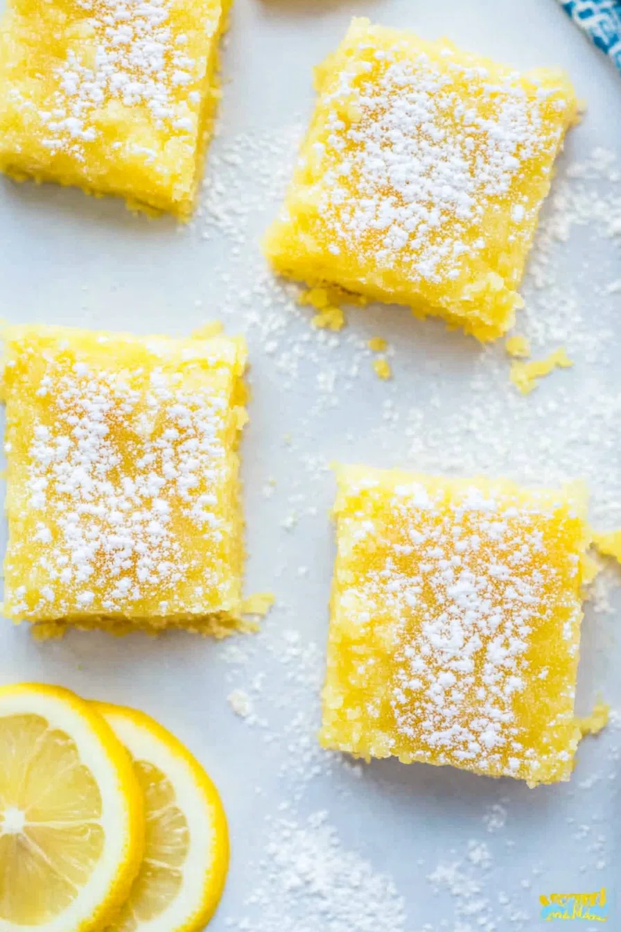 An overhead shot of several lemon bars arranged neatly on a white serving platter.