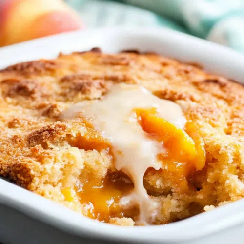 A side view of a spoonful of peach cobbler, showcasing the layers of fruit and crust.