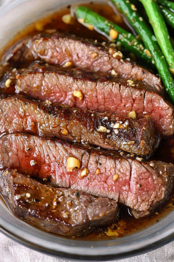 Close-up of succulent steak pieces garnished with fresh herbs, highlighting the marinade's shine.