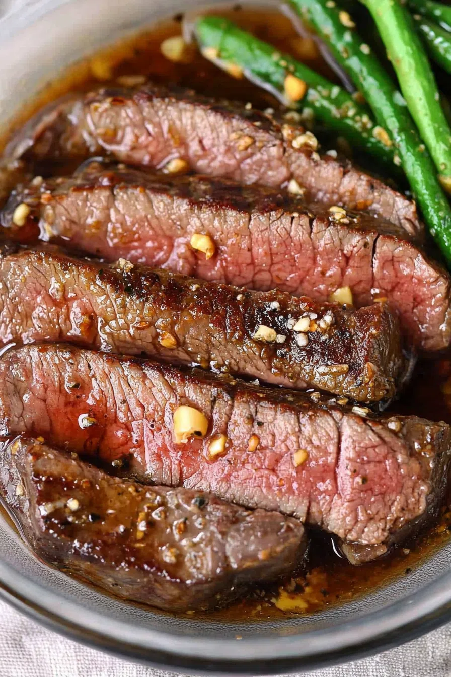Close-up of succulent steak pieces garnished with fresh herbs, highlighting the marinade's shine.