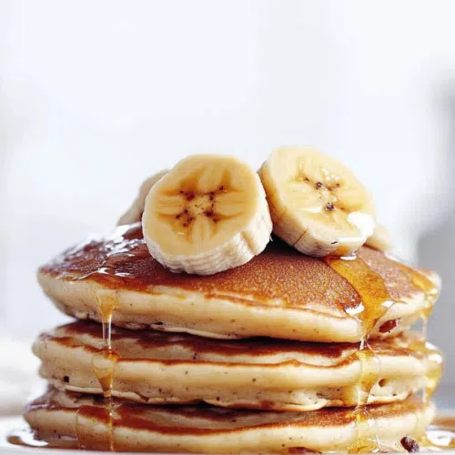 A close-up of fluffy and light pancakes drizzled with maple syrup.