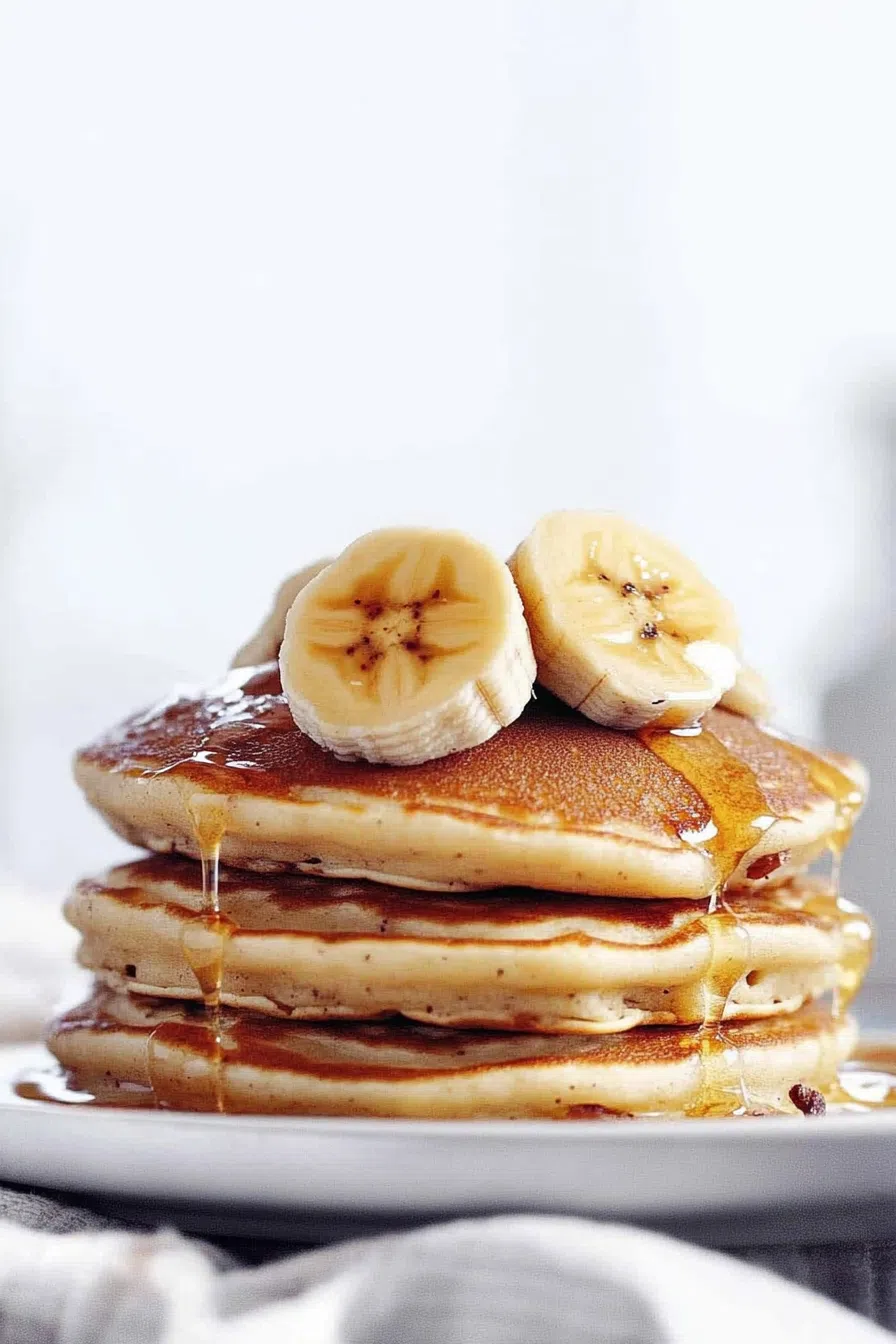 A close-up of fluffy and light pancakes drizzled with maple syrup.