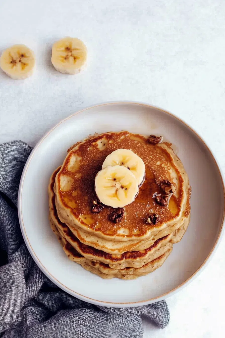 A plate of pancakes with a tender, moist interior, garnished with fresh fruit.