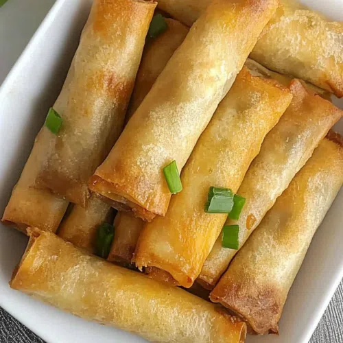 Delicious lumpia arranged in a circular pattern on a white plate, with a garnish of fresh herbs.