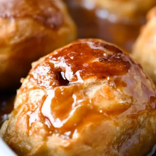 A close-up of a perfectly baked apple dumpling with a flaky crust.