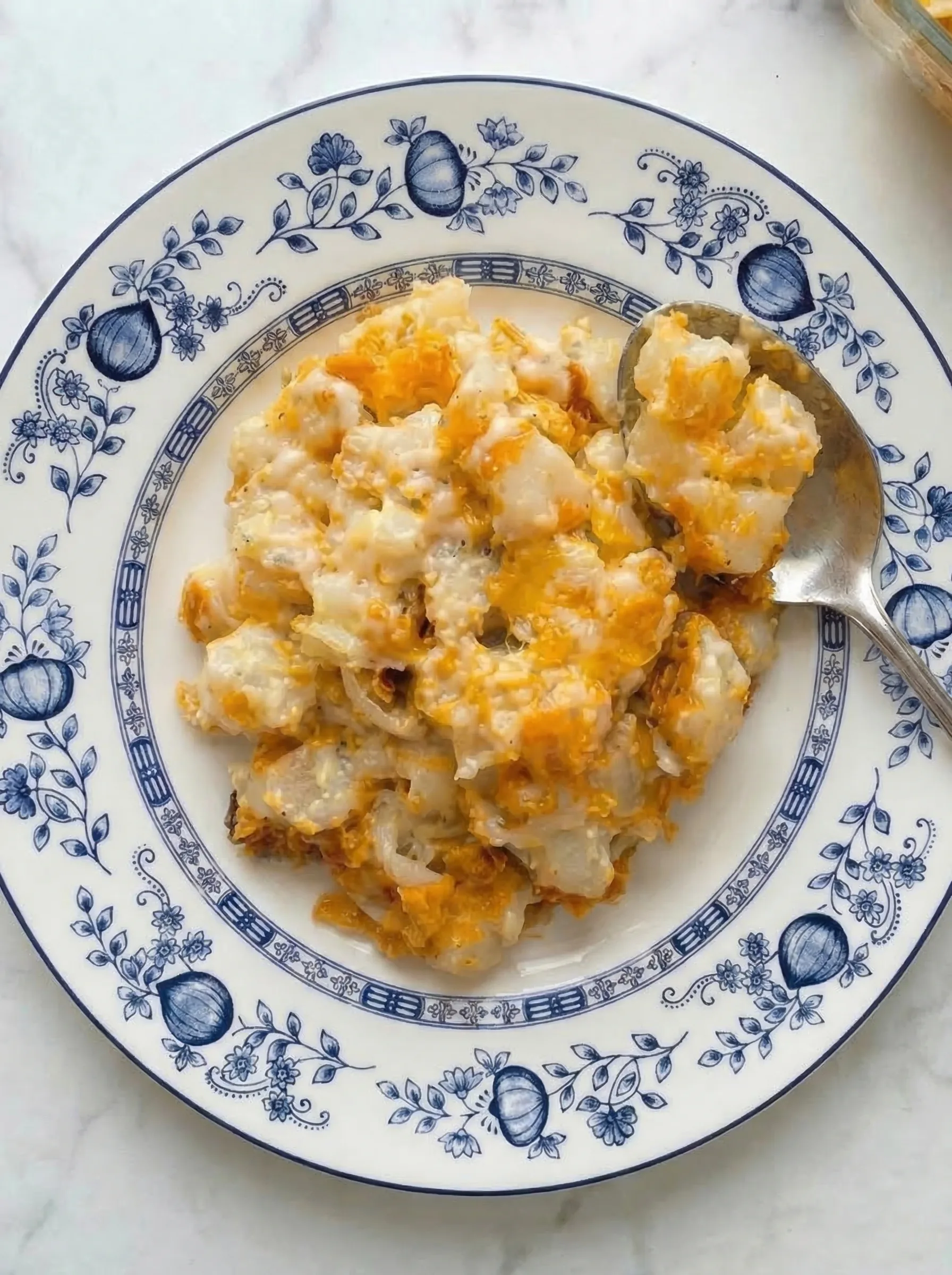 Serving of Amish Funeral Potatoes on a plate showing creamy texture and melted cheddar cheese