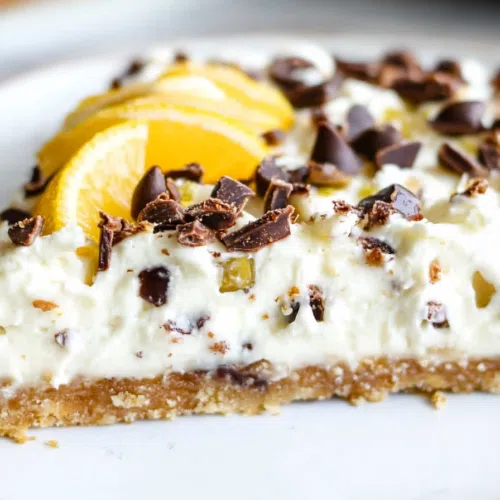 A sliced piece of Cannoli Pie on a plate, showcasing the buttery crust and creamy, chocolate-studded filling.