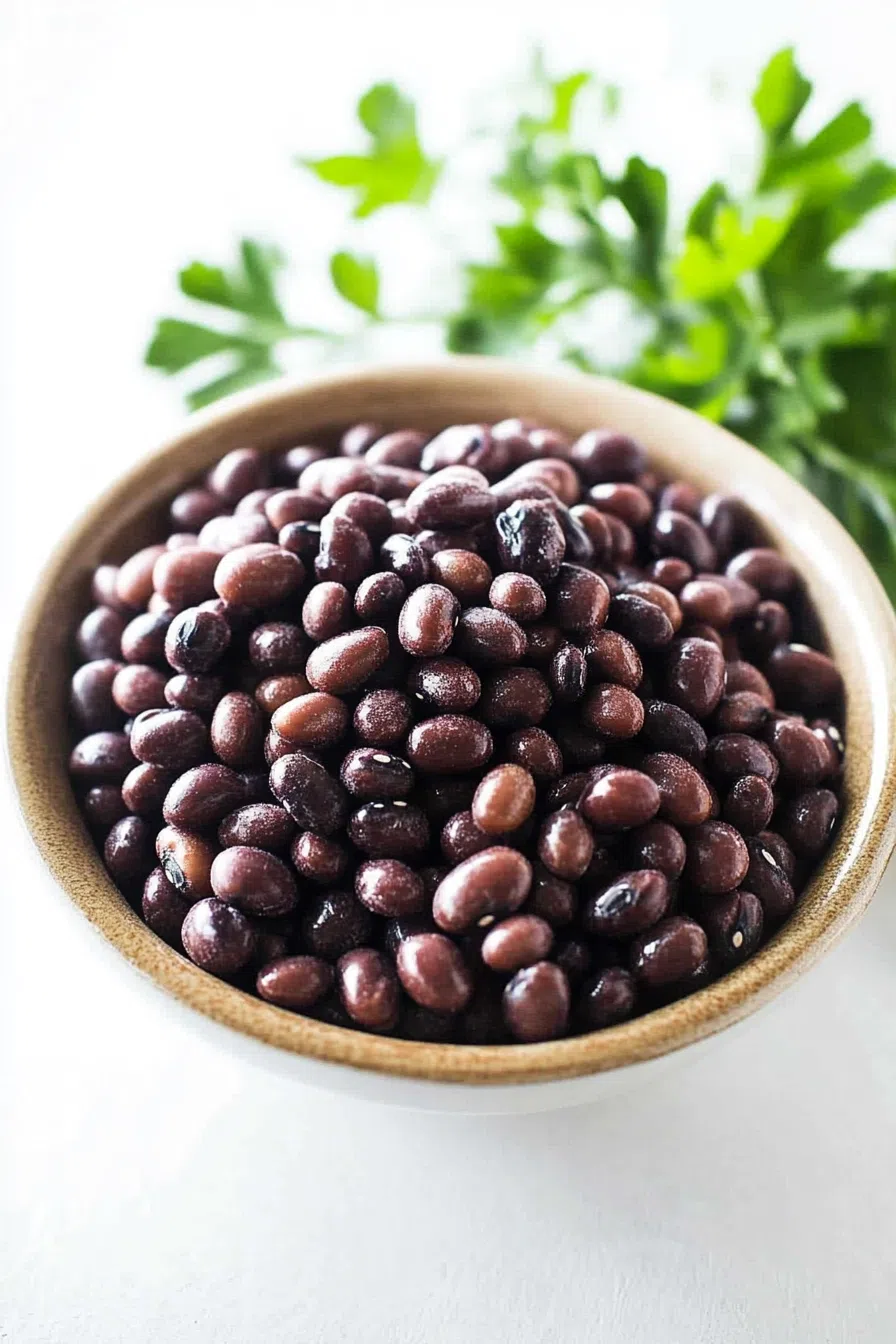 A bowl of tender, cooked beans served with a sprinkle of fresh herbs.