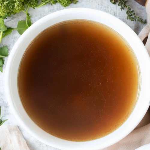 Close-up of the rich and clear lamb bone broth, highlighting the floating bits of tender lamb.