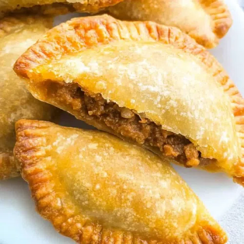 A beautifully presented pastelito with visible layers of pastry and seasoned beef filling.