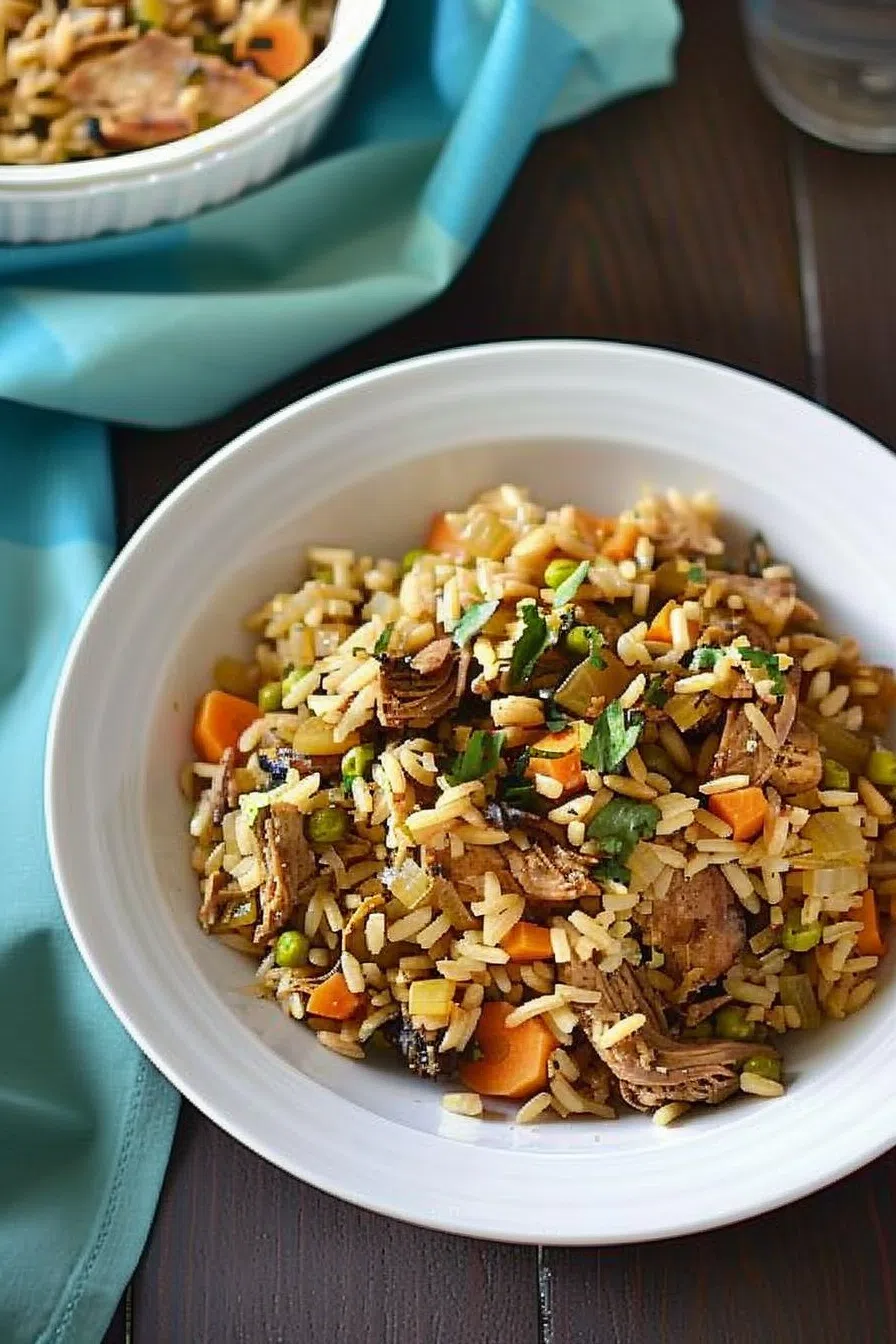 A vibrant bowl of Trinidad Chicken Pelau featuring golden-brown rice, tender chicken pieces, and colorful vegetables like carrots and peas, garnished with fresh herbs.