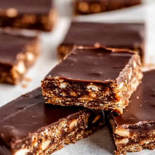 A stack of vegan gluten-free protein bars with a bite taken out of one, showing the texture.