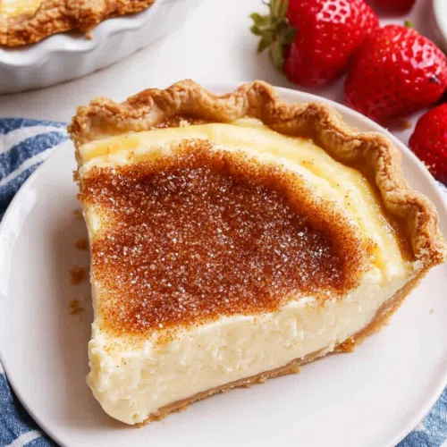 A creamy, custard-like pie with a golden-brown crust and a dusting of cinnamon on top.