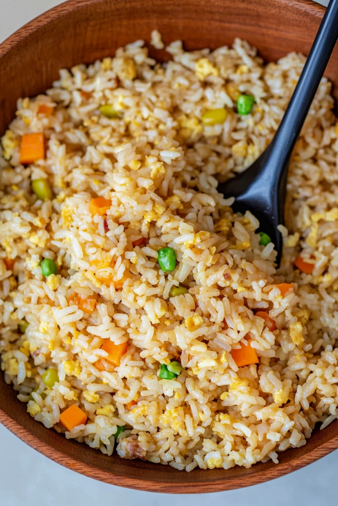 A close-up of a plate of golden, pan-fried rice mixed with diced vegetables.