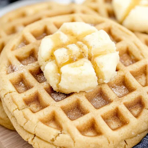 Golden waffle-shaped cookie drizzled with syrup and a dollop of butter on top.