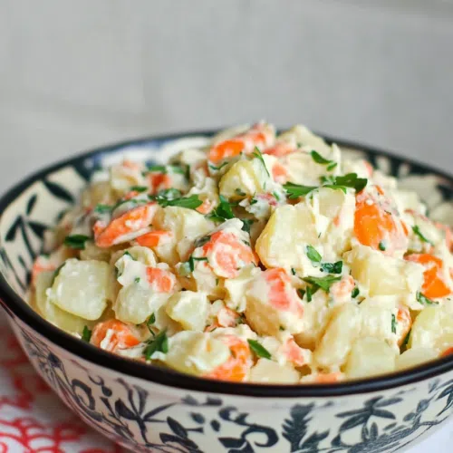 Bowl of vibrant Dominican potato salad with colorful vegetables.