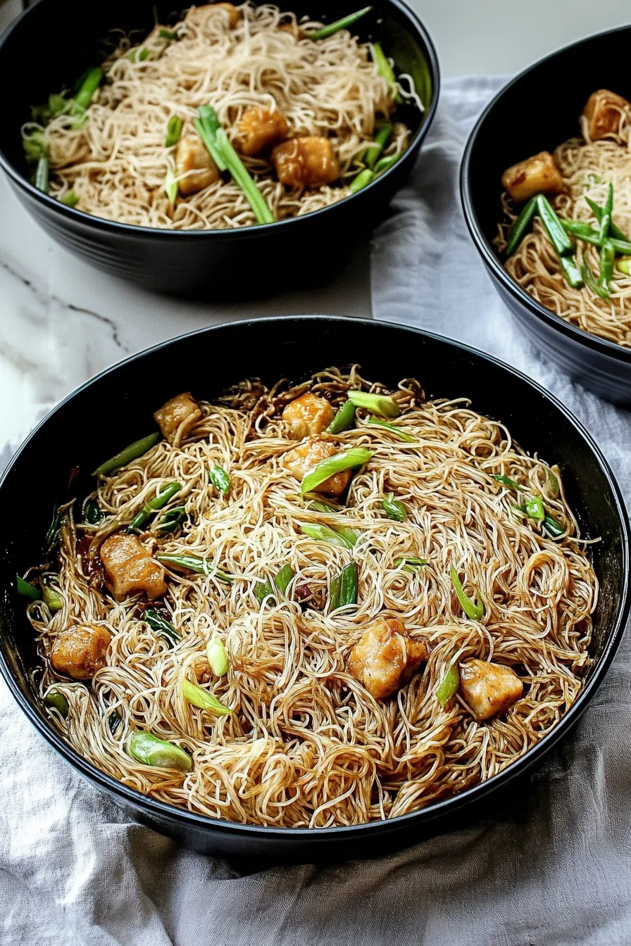 A serving of noodles with chicken and garnished with green onions.