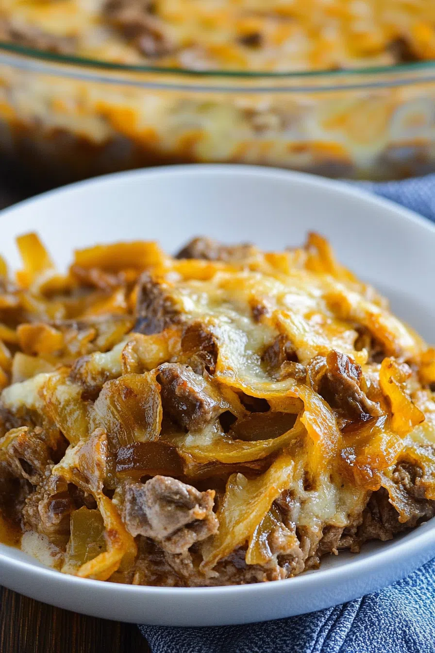 A serving of hearty beef casserole on a plate, showing tender layers of meat, pasta, and melted cheese.