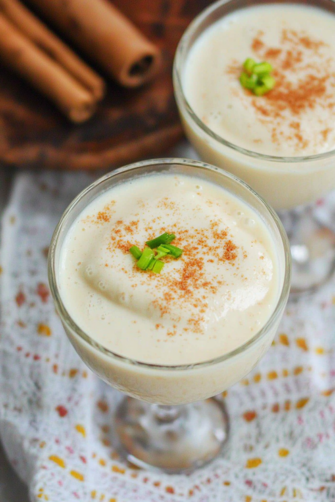 A creamy cocktail in a decorative glass, garnished with grated nutmeg.