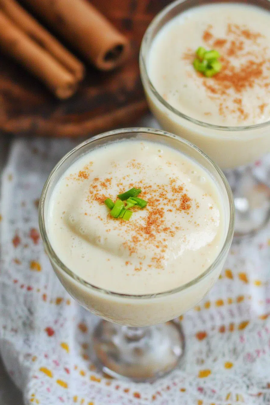 A creamy cocktail in a decorative glass, garnished with grated nutmeg.