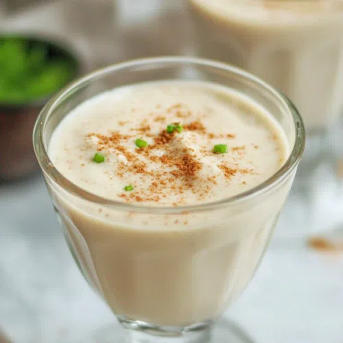 Glass of creamy, spiced Haitian cremas topped with a sprinkle of nutmeg.