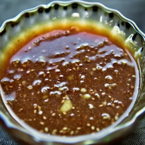 A small dish filled with a rich, glossy sauce on a wooden table.