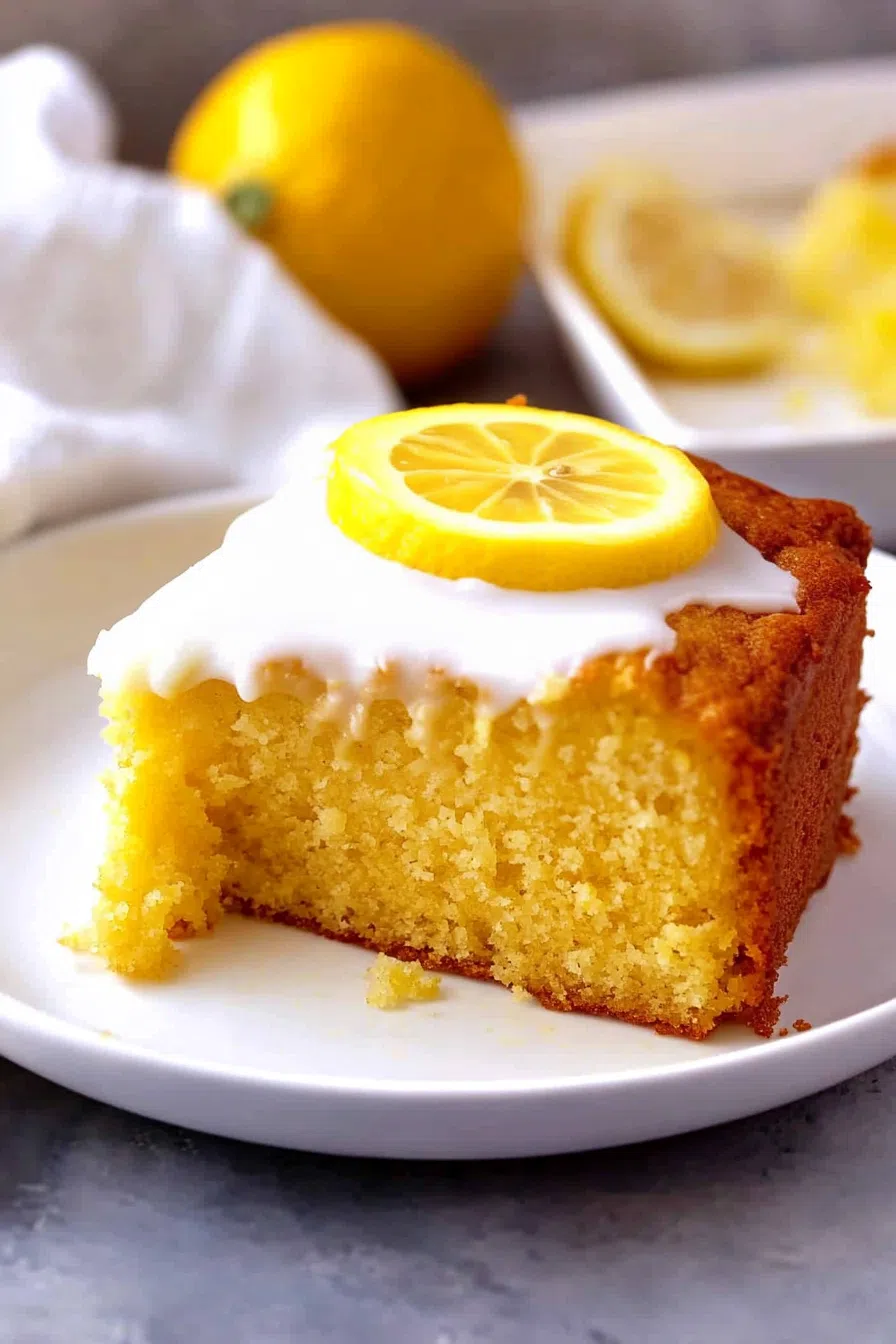 Bright and airy cake displayed on a serving platter with fresh lemon slices on the side.