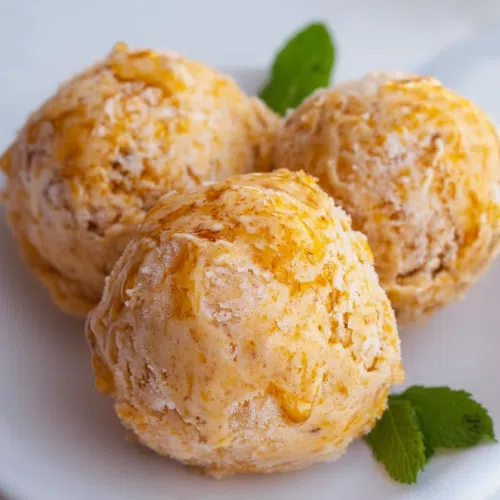 Close-up of ice cream topped with caramel drizzle and crushed nuts.