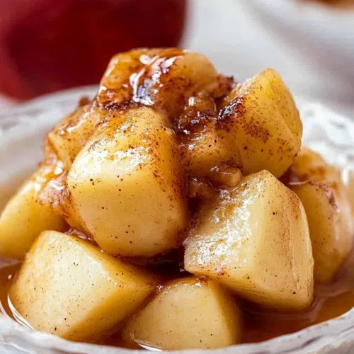 A baked apple filled with a sweet, spiced topping in a white bowl.