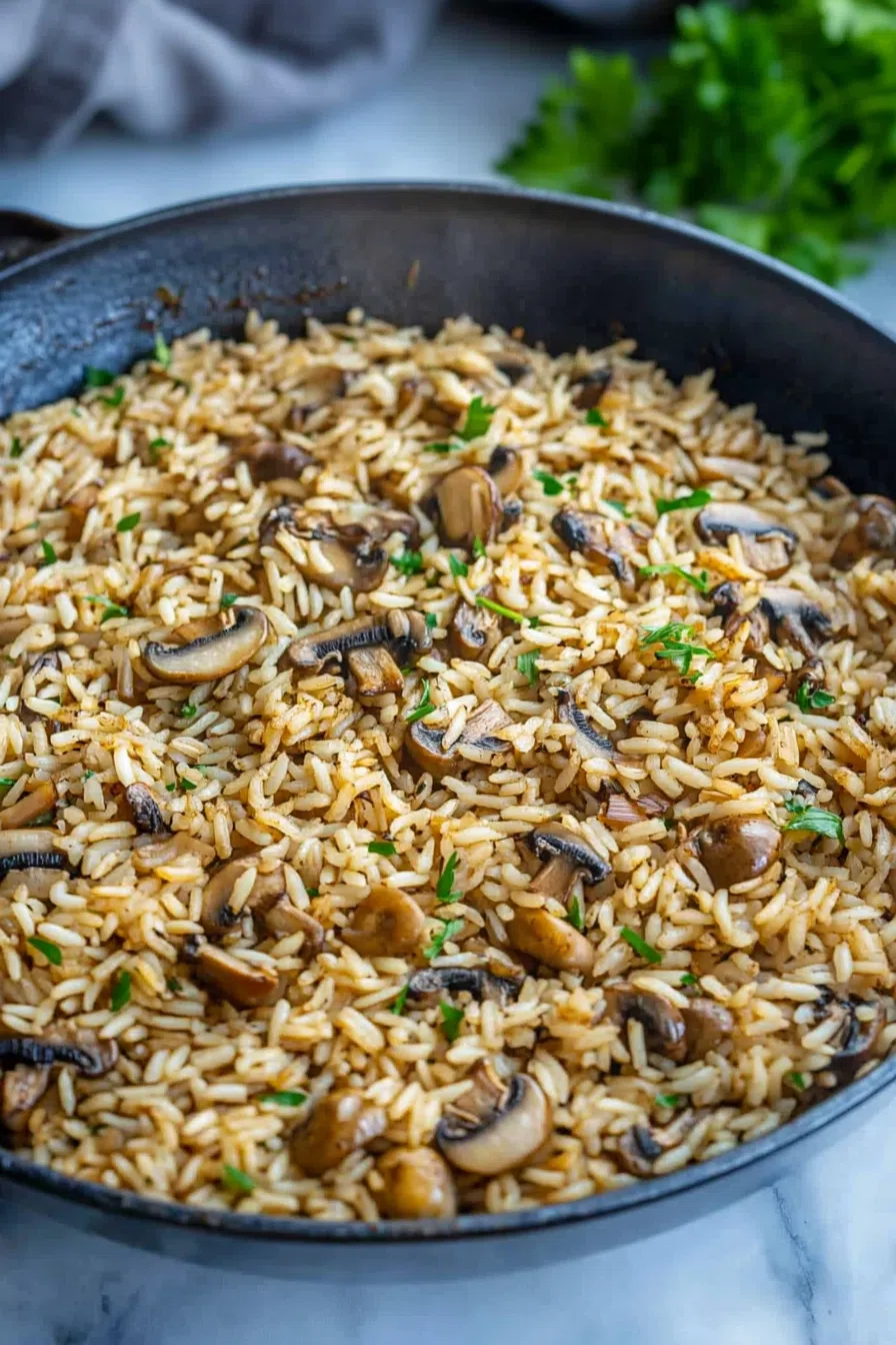 A skillet filled with tender mushrooms and perfectly cooked rice.
