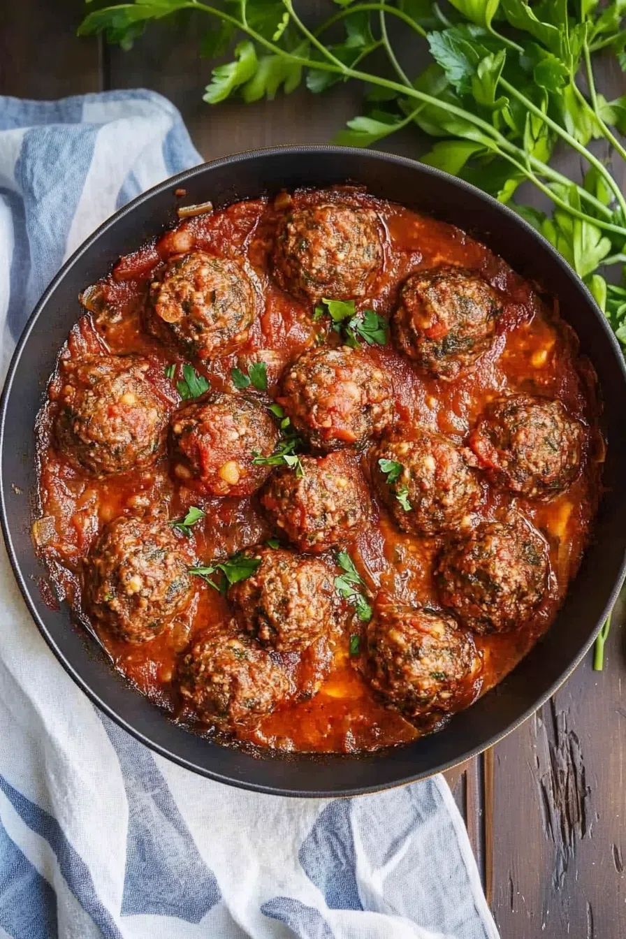 Meatballs in a deep skillet, coated in a thick, flavorful sauce.