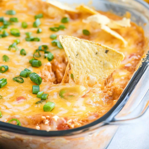 A tortilla chip scooping up a creamy, melted cheese dip.