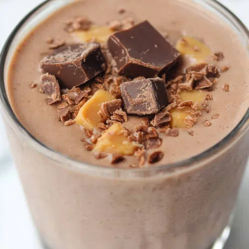 Close-up of a thick, rich smoothie garnished with a dollop of whipped cream.