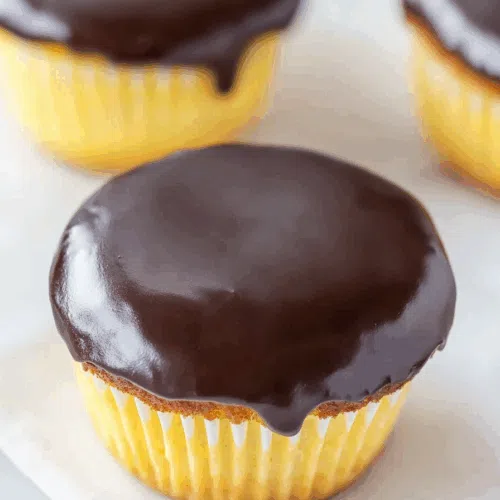 Close-up of cupcakes topped with glossy chocolate ganache.