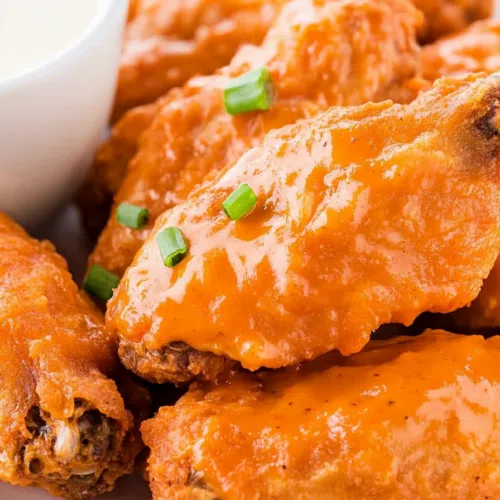 Close-up of saucy wings with charred edges.