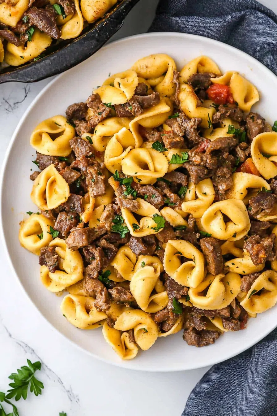 Tortellini in a rich white sauce served on a rustic plate with sautéed peppers and onions.
