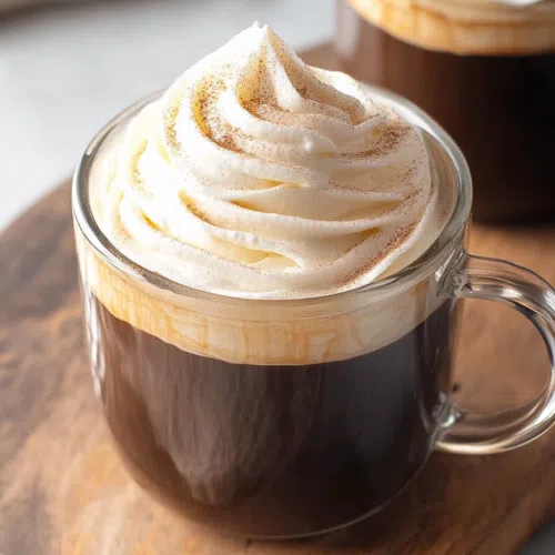 Overhead view of a smooth, airy topping next to a cup of espresso.