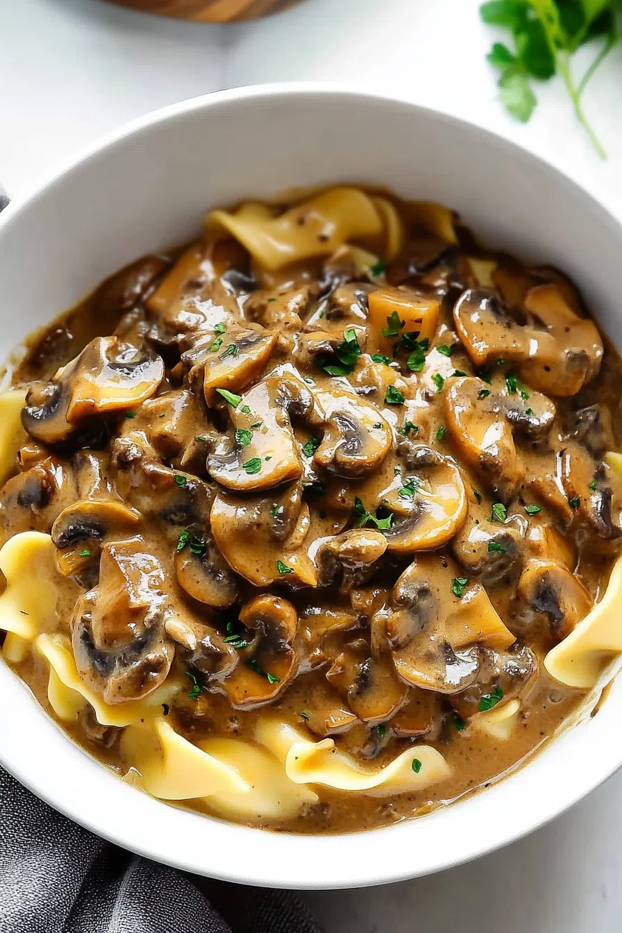 Overhead view of a plated meal with rich sauce and browned mushrooms.