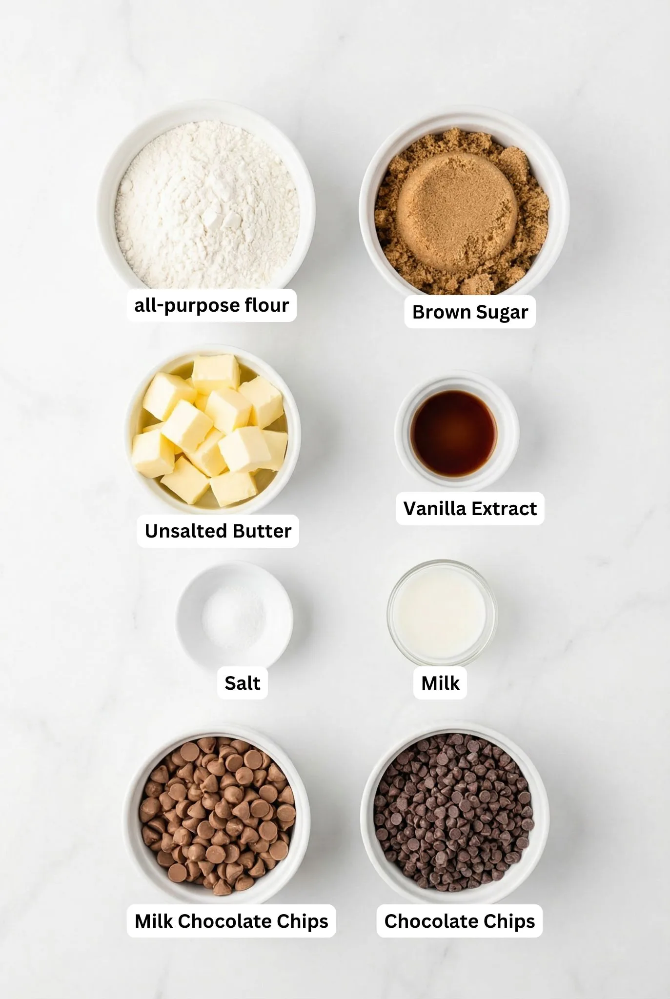 Flat lay of flour, brown sugar, butter, milk, vanilla, salt, and chocolate chips arranged in white bowls for an Edible Cookie Dough Recipe