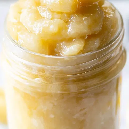 Close-up of a jar filled with a golden, fruity spread.