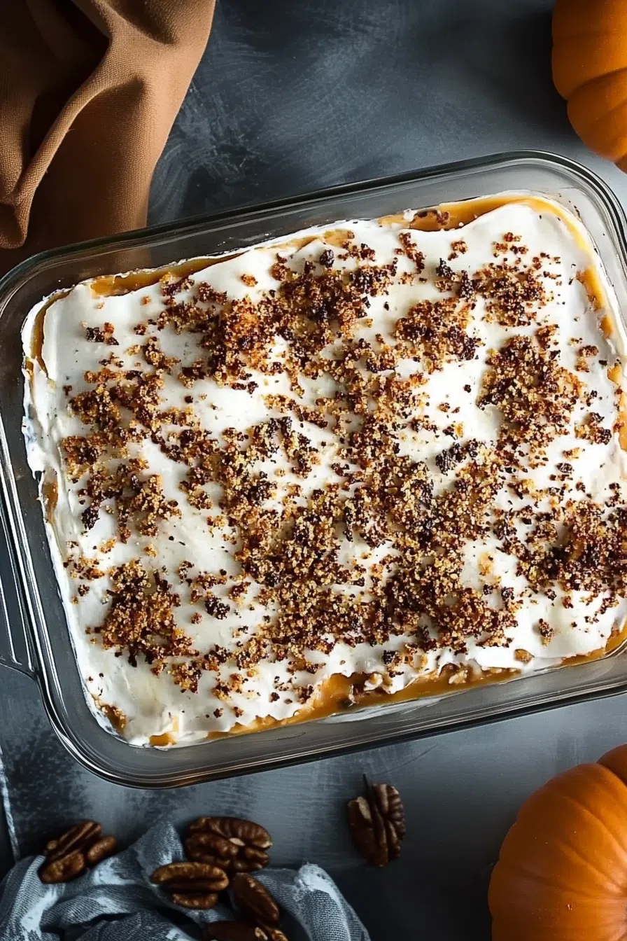 A layered dessert with whipped topping and crushed pecans in a glass dish.