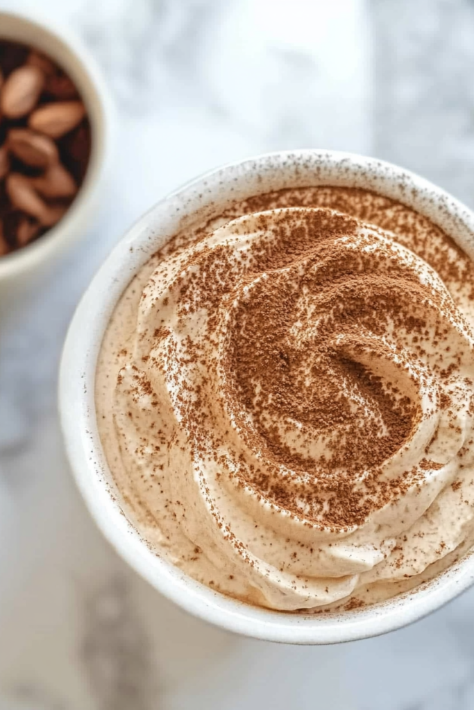 Overhead view of a dessert platter with dip, cookies, and cocoa garnish.
