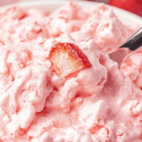 Close-up of a creamy fruit salad topped with mini marshmallows.