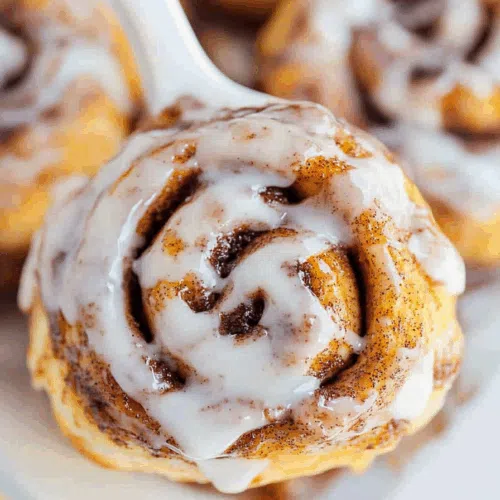 A single cinnamon roll being pulled apart, revealing the soft center.