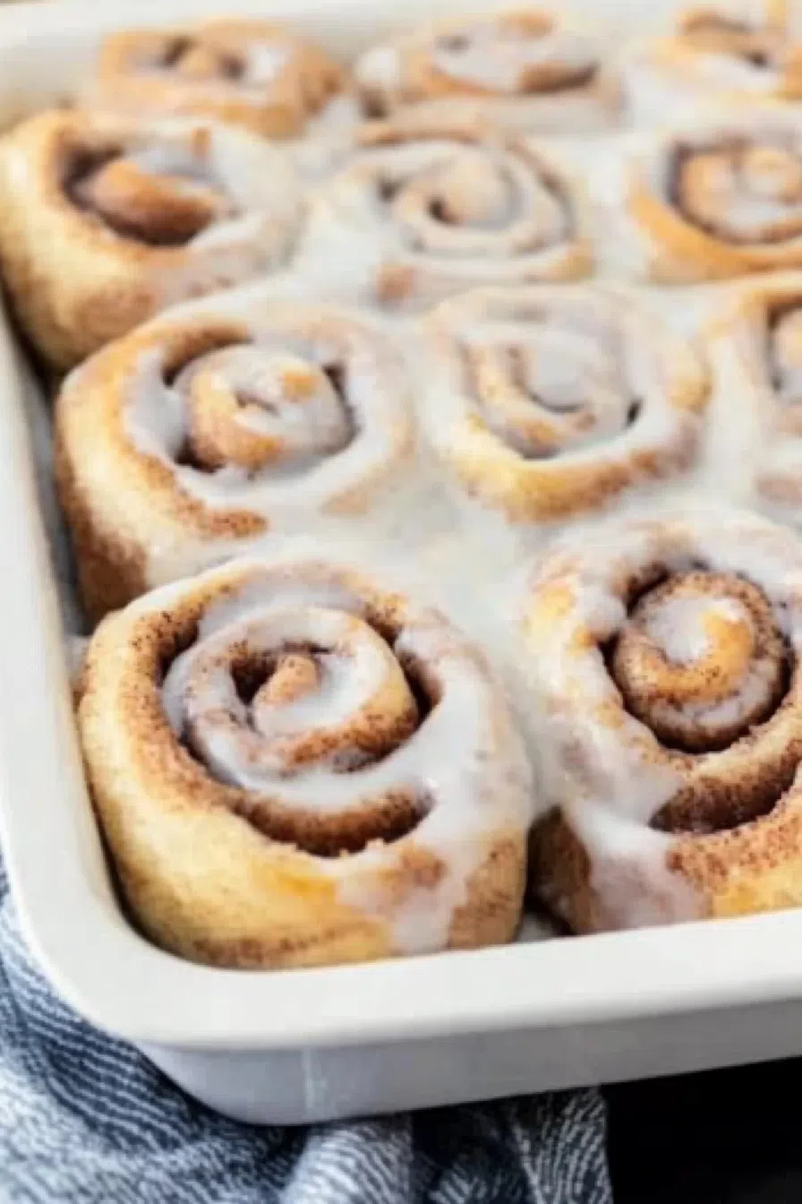 Overhead view of a baking dish filled with golden, frosted rolls.