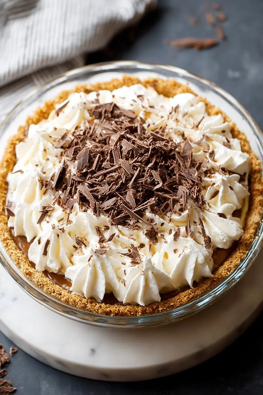Top-down view of a chilled pie with swirled cream and chocolate drizzle.