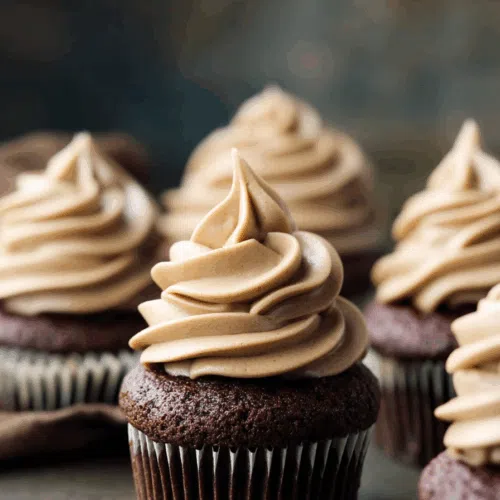 Close-up of rich, frosted cupcakes topped with chocolate shavings.