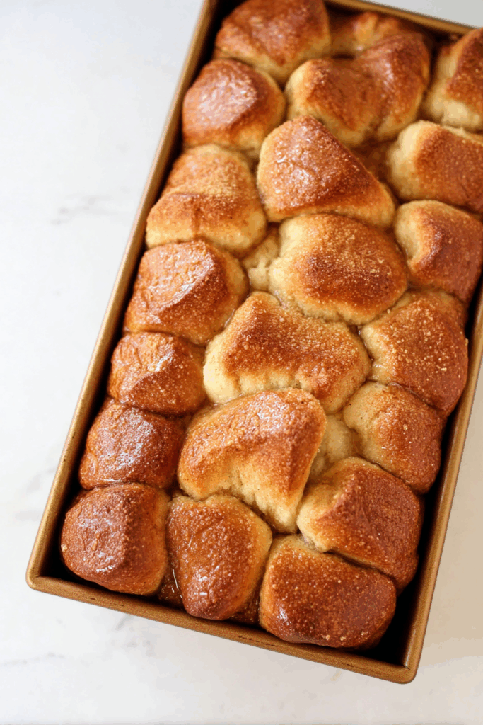 Overhead shot of gooey baked bread pieces stacked neatly in a pan.