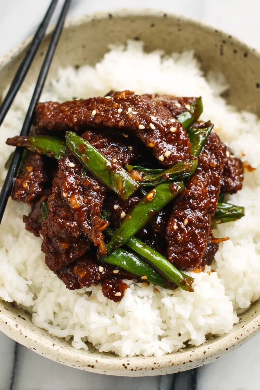 Dinner setting featuring a full plate of glazed meat and rice, garnished with sesame seeds.